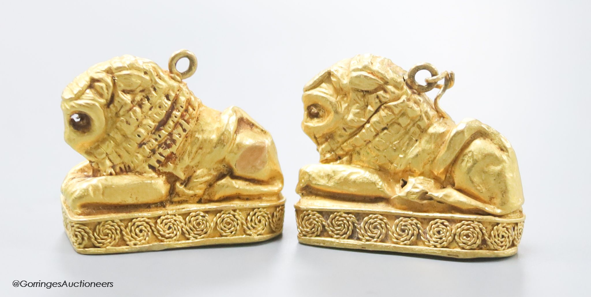 A pair of Etruscan style yellow metal recumbent lion pendant charms, 25mm, gross 11.1 grams (tests as 22ct)